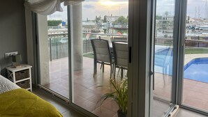 Una habitación con un gran ventanal corredizo que da a un balcón con vistas a un puerto deportivo y barcos.
