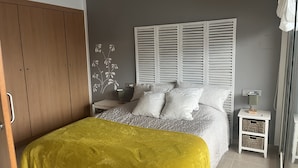 Un dormitorio con cama, armario, mesita de noche y lámpara.