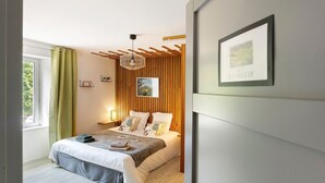 Ein Schlafzimmer mit einem Bett, Nachttischen, einer Hängeleuchte, einem Fenster mit Vorhängen und einem gerahmten Bild an der Wand.
