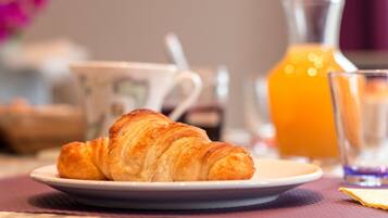Un croissant sur une assiette, un verre de jus d’orange et une tasse avec une cuillère.