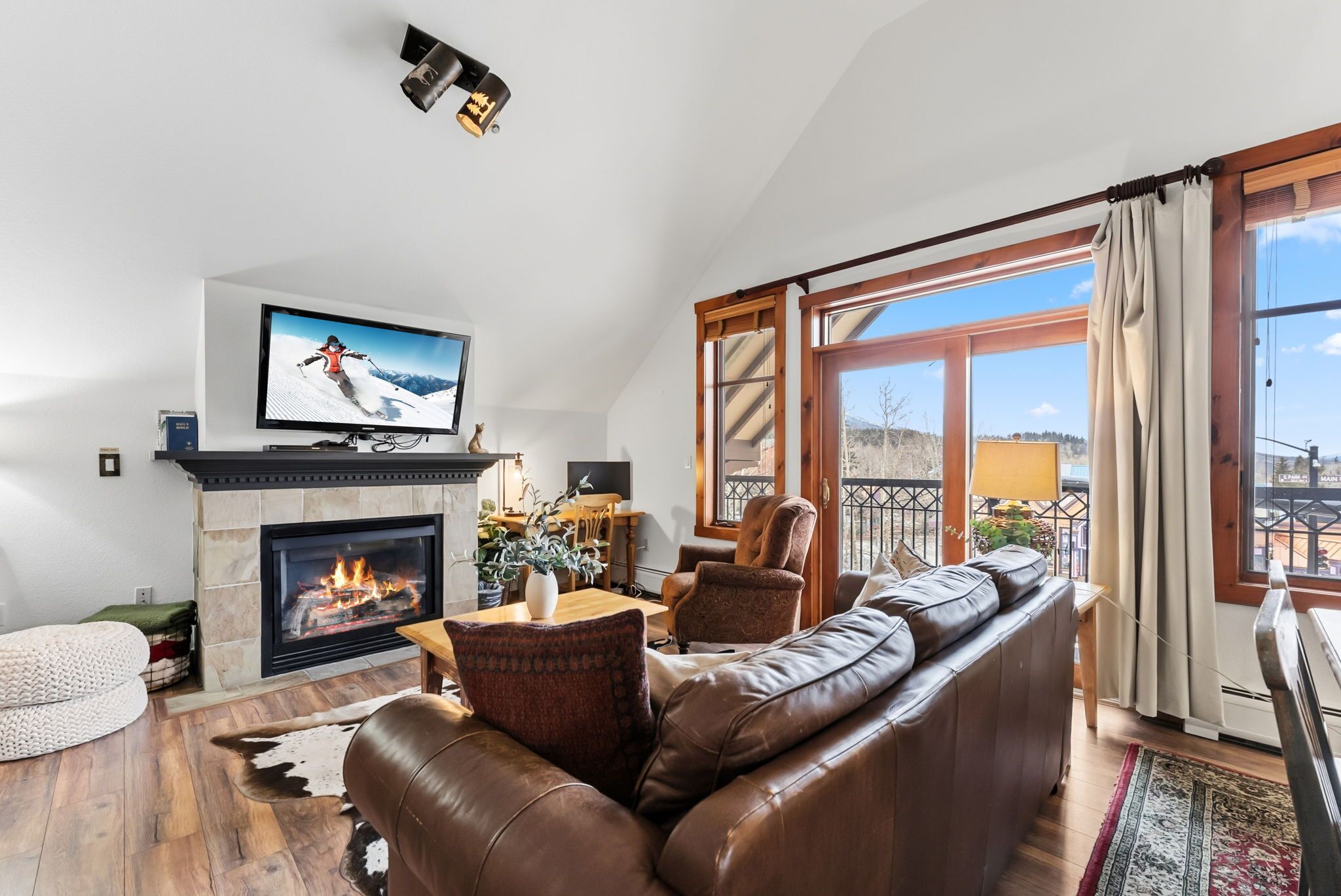 Una sala de estar con chimenea, sofá de cuero y televisión montada en la pared.