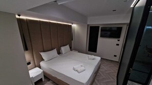 A modern hotel room with a large bed, a bedside table, and a TV mounted on the wall.
