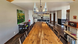 Un vaste espace dédié à la salle à manger, avec une longue table en bois, des appareils de cuisine modernes et une cheminée.
