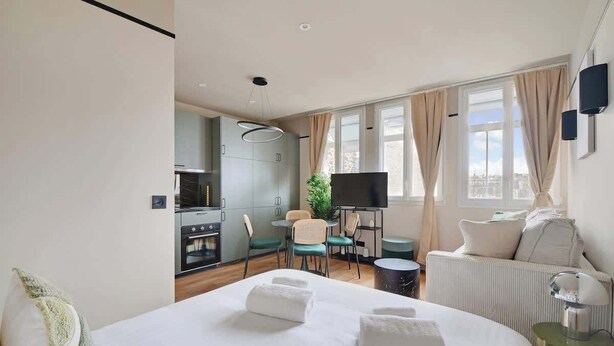 Une chambre d’hôtel moderne dotée d’un grand lit, d’un coin repas, d’une télévision et offrant une vue sur la ville.