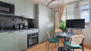 Une cuisine moderne avec des meubles gris, une cuisinière noire et un coin repas comprenant une table et des chaises.