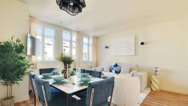 Una sala moderna con comedor, que incluye un sofá, una mesa de centro y una mesa de comedor con platos y vasos.