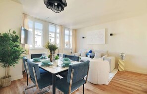 Een moderne woonkamer met een eethoek, voorzien van een bank, salontafel en een eettafel gedekt met borden en glazen.
