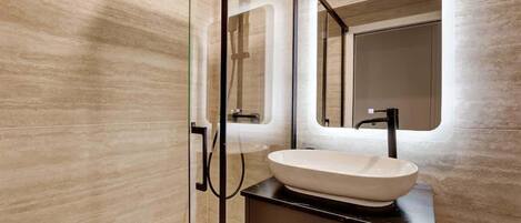 A modern bathroom with a glass shower enclosure, a large mirror, and a vessel sink.