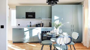 Una cocina moderna con armarios azul claro, un horno negro y un comedor con mesa dispuesta para cuatro.