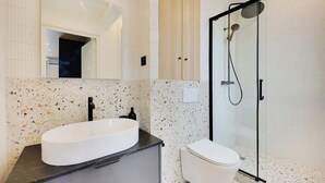 Ein modernes Badezimmer mit freistehender Waschtasche, Toilette und einer Duschkabine aus Glas.