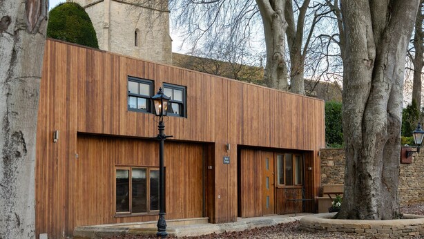 Ein modernes Gebäude mit Holzfassade, großen Fenstern und einer Steinwand.