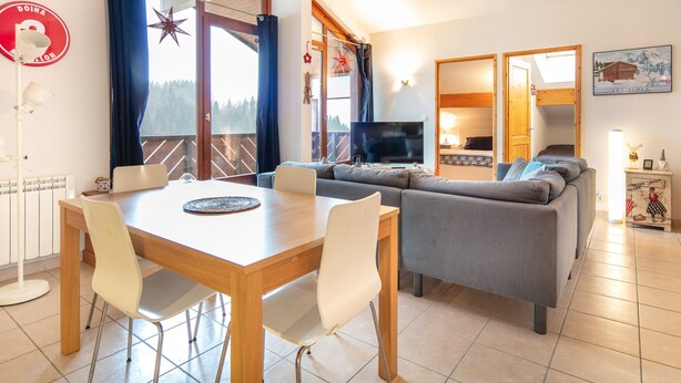A modern living room with a dining area, a sofa, a TV, and a balcony with a star decoration. - Splendid apartment, 3 bedrooms, sleeps 6, balcony with mountain views (Morillon)