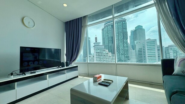 Ein modernes Wohnzimmer mit großem Fenster, Flachbildfernseher, Couchtisch und einer Couch.