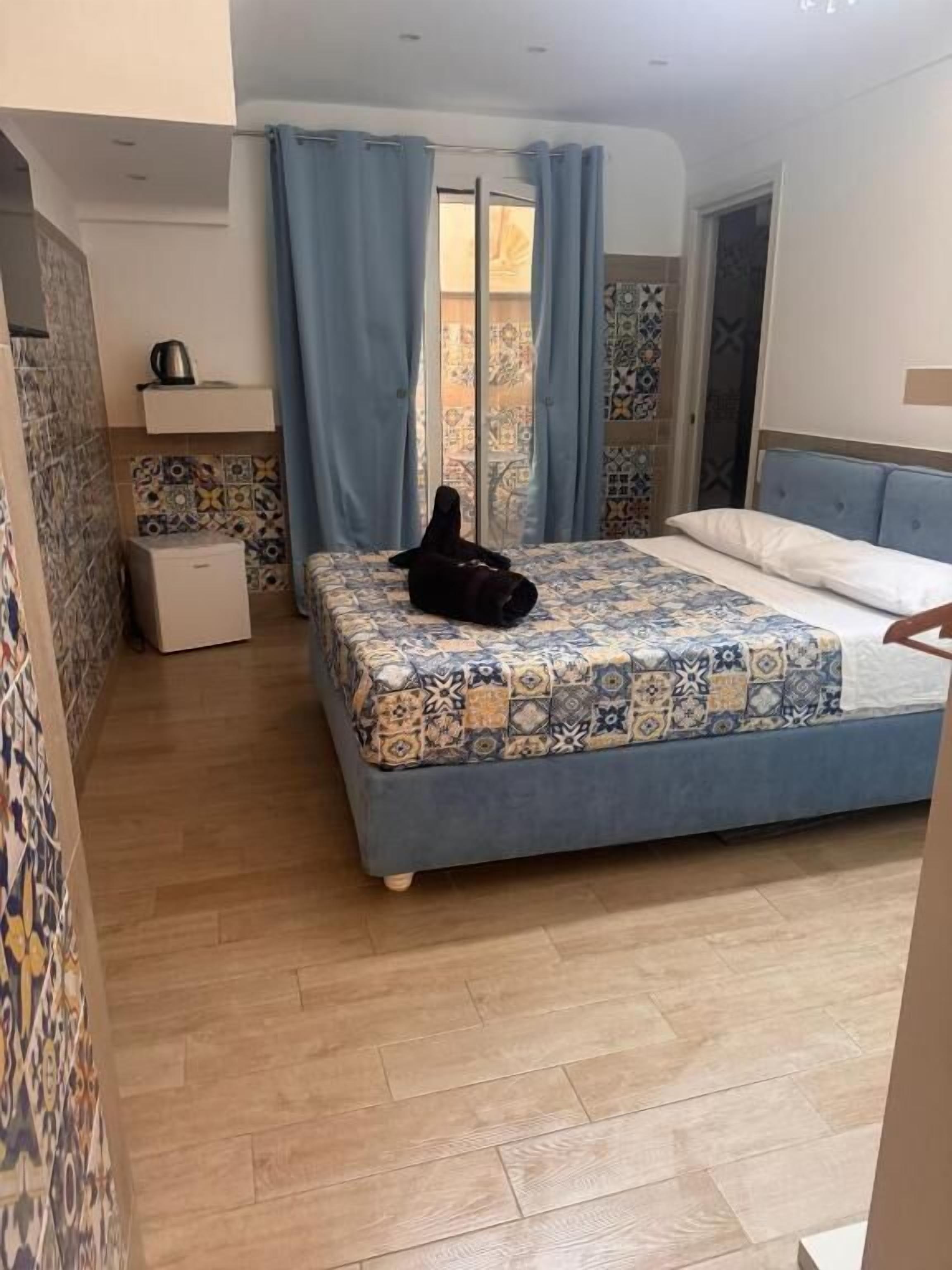 Een slaapkamer met een bed, een klein nachtkastje, een kledingkast en een zichtbare badkamer door een glazen deur.