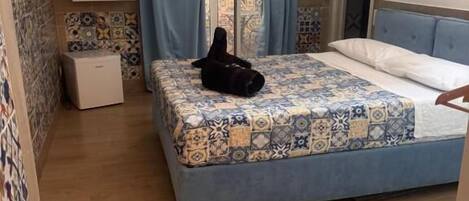 Een slaapkamer met een bed, een klein nachtkastje, een kledingkast en een zichtbare badkamer door een glazen deur.