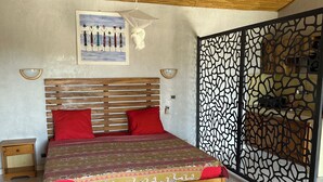 A bedroom with a wooden bed, red pillows, a wall-mounted clock, and a decorative panel.
