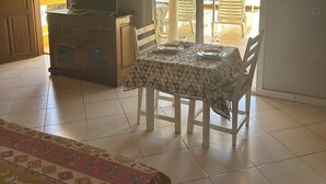 A room with a bed, a table with chairs, a television, and a sliding glass door leading to an outdoor area with a table and chairs.