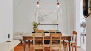 A dining area with a wooden table and chairs, a framed artwork above, and a vase with flowers on the table. - A Breathtaking 2-BR/1Ba - Gobelins (Paris)