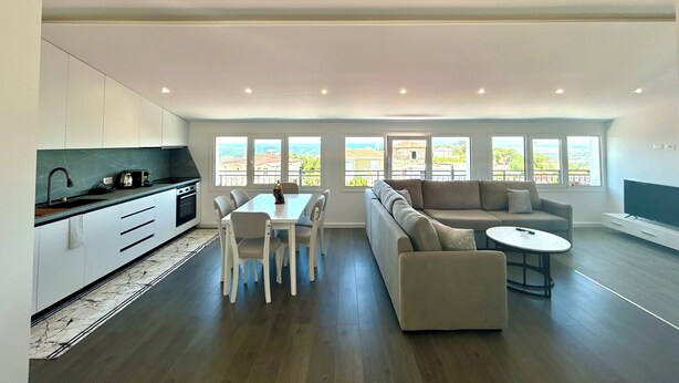 A modern living space with a kitchen, dining area, and seating area with large windows. - Ishem • Penthouse • Free Wi-Fi • 2 Balconies • Green View • Garden •Pet-Friendly (Ishëm)