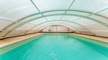 An indoor swimming pool with a curved ceiling and clear glass walls.