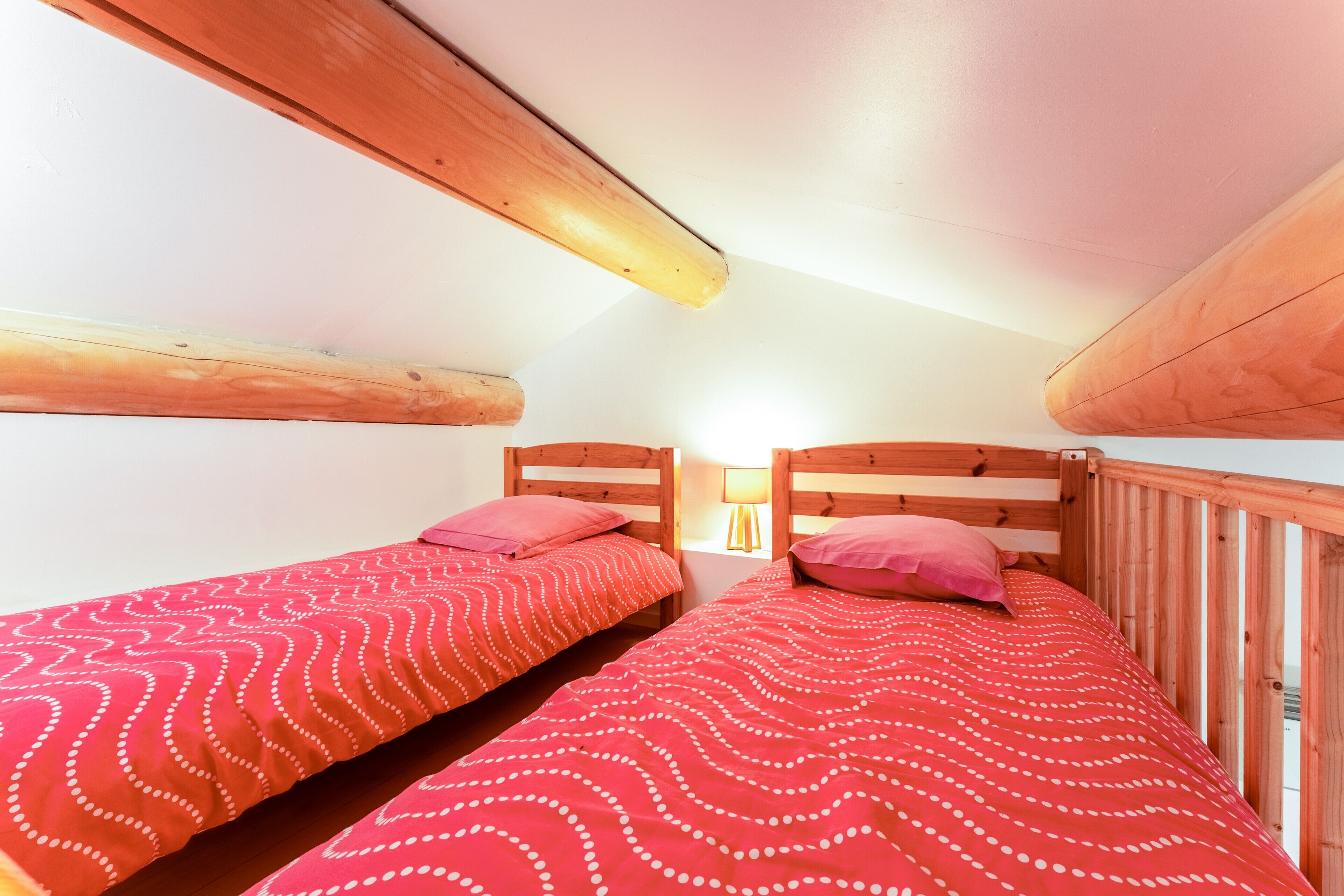 A bedroom with two beds, wooden headboards, and a nightstand with a lamp.