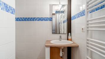 A bathroom with white tiles, a wooden sink, and a towel rack.