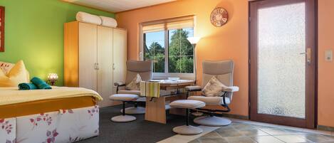 A bedroom with a bed, a desk, two chairs, a wardrobe, and a door.