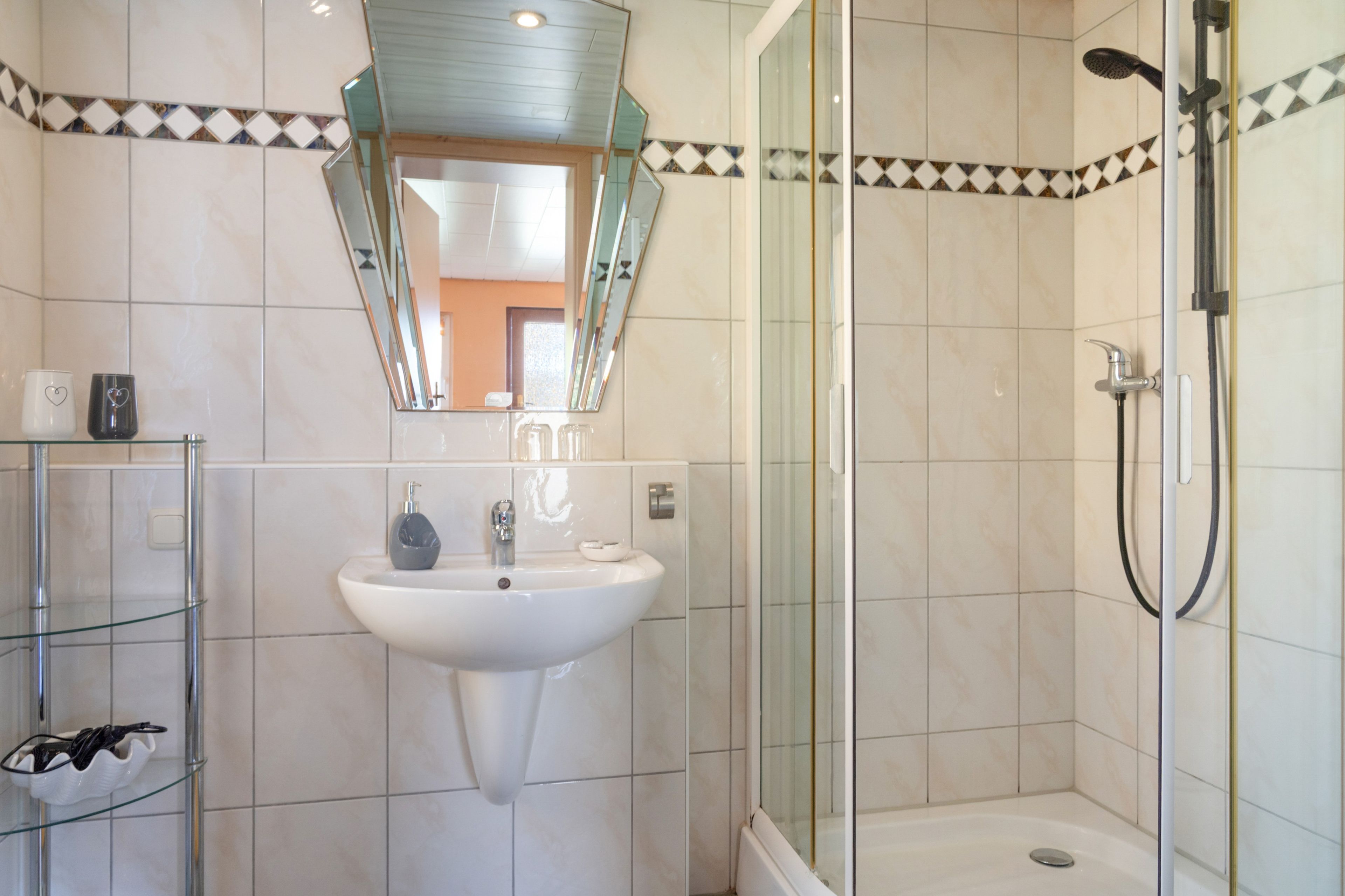 A bathroom with a glass shower enclosure, a white sink, and a mirror above the sink.