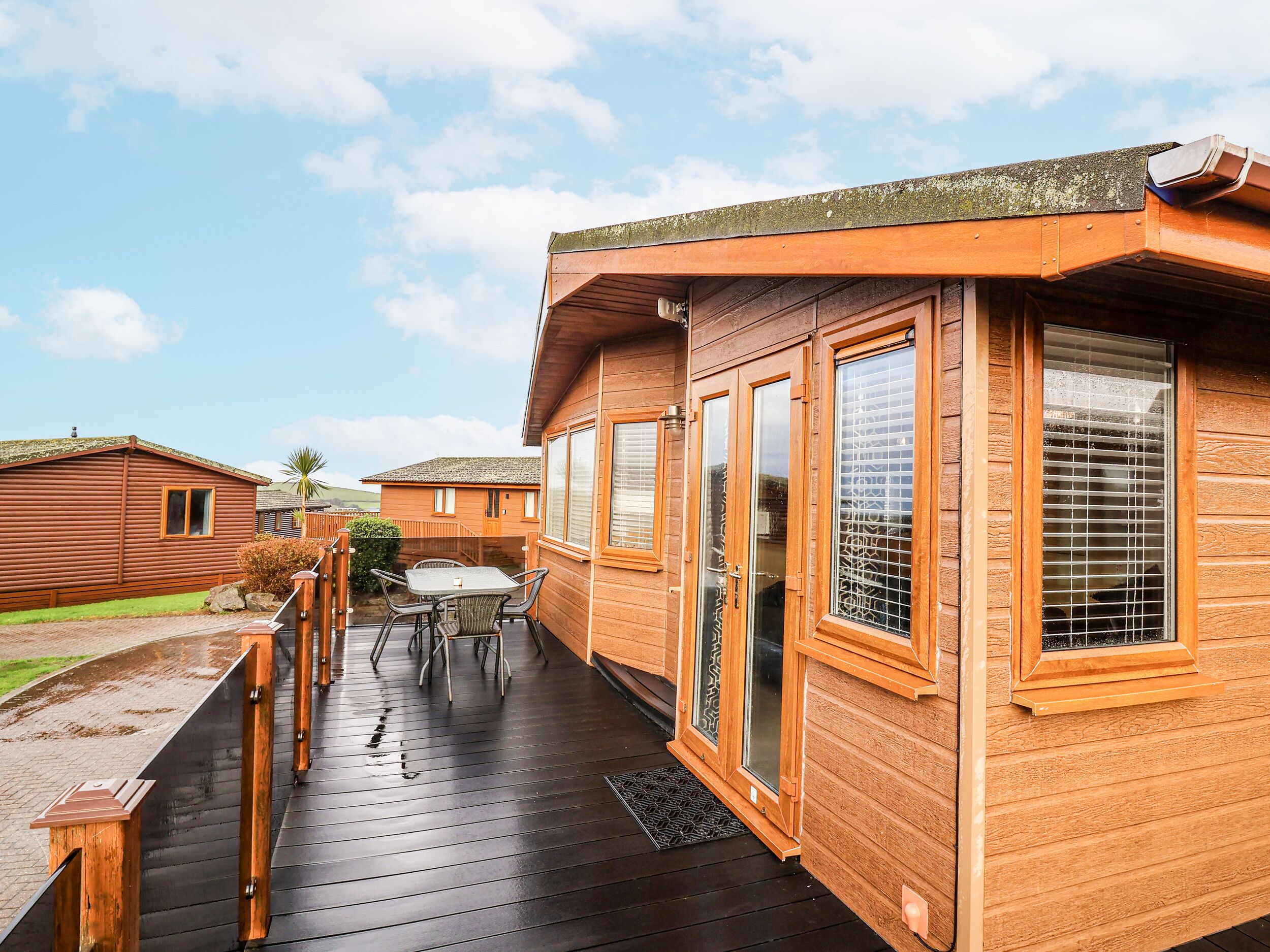 A wooden cabin with a deck, a table, and chairs.