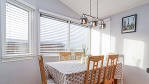 A dining area with a table set for four, wooden chairs, and a pendant light fixture. - Ocean View (Ilfracombe)