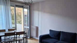 Un soggiorno moderno con un divano blu scuro, un tavolino in legno e una zona pranzo con tavolo e sedie.