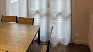 Una stanza con un tavolo da pranzo in legno, sedie e un'ampia finestra con vetri decorati.