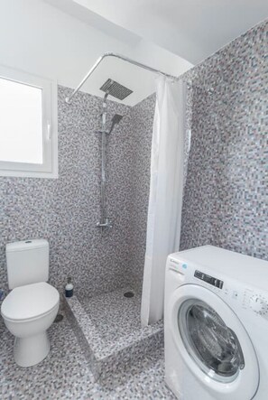 A bathroom with a shower, toilet, and washing machine. - Romantic Island in the Sky, Acropolis & City Views (Athina)