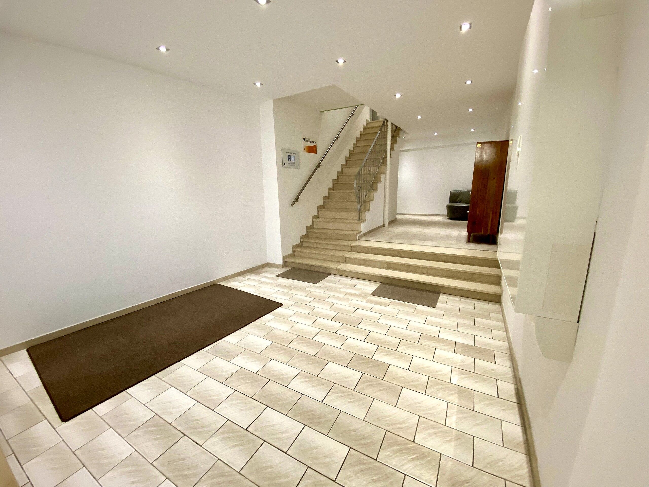Eine Treppe führt zu einer oberen Etage, mit einer Handläufe und einem Teppichbelag versehenen Zwischenpodest.