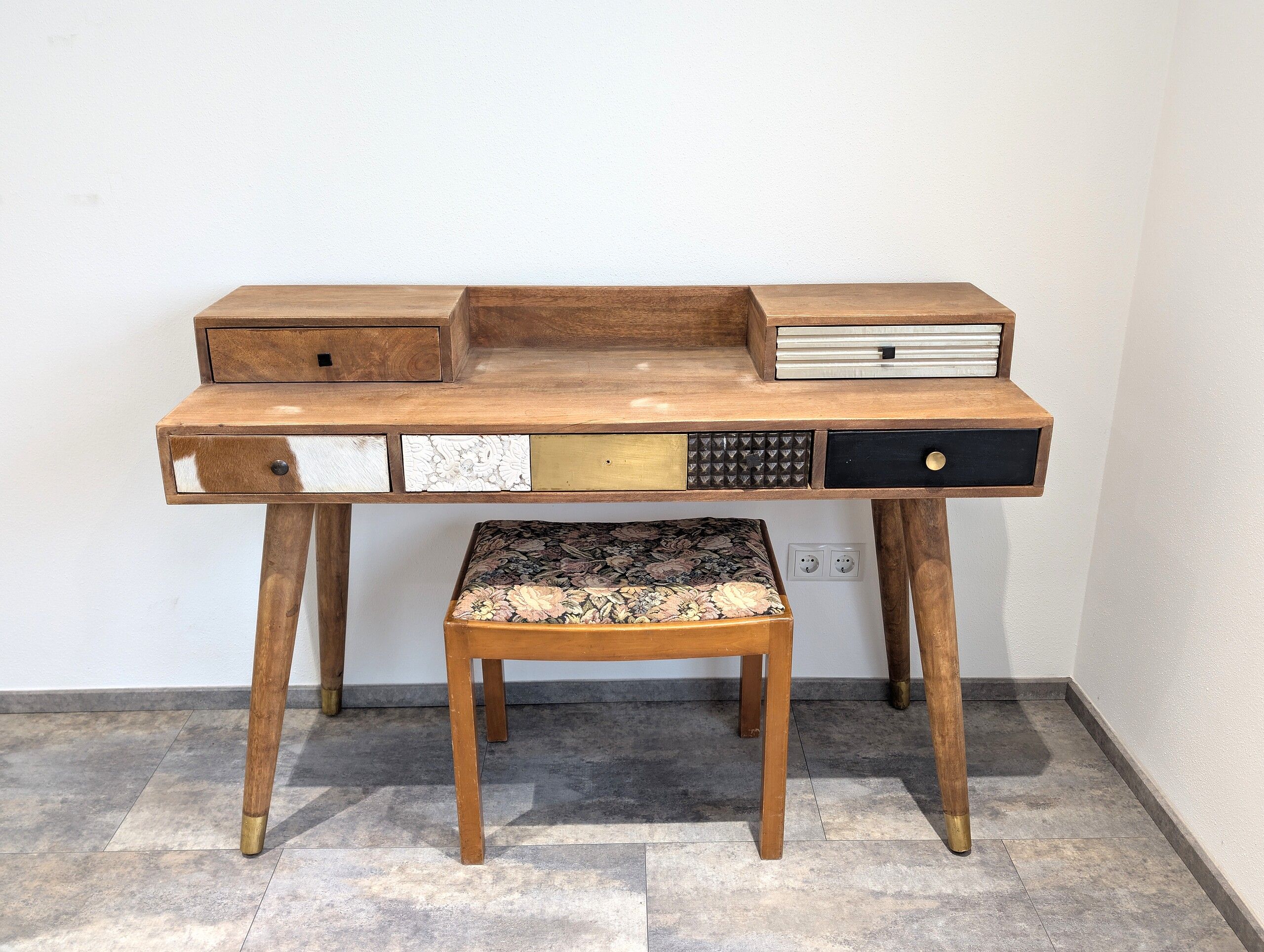Un bureau en bois avec des tiroirs et un tabouret rembourré.