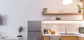 A modern kitchen with a stainless steel refrigerator, a coffee maker, and a sink. There are wooden cabinets and a marble countertop. - Kypseli's Dreamy Studio Your Cosy Greek Oasis! (Athina)