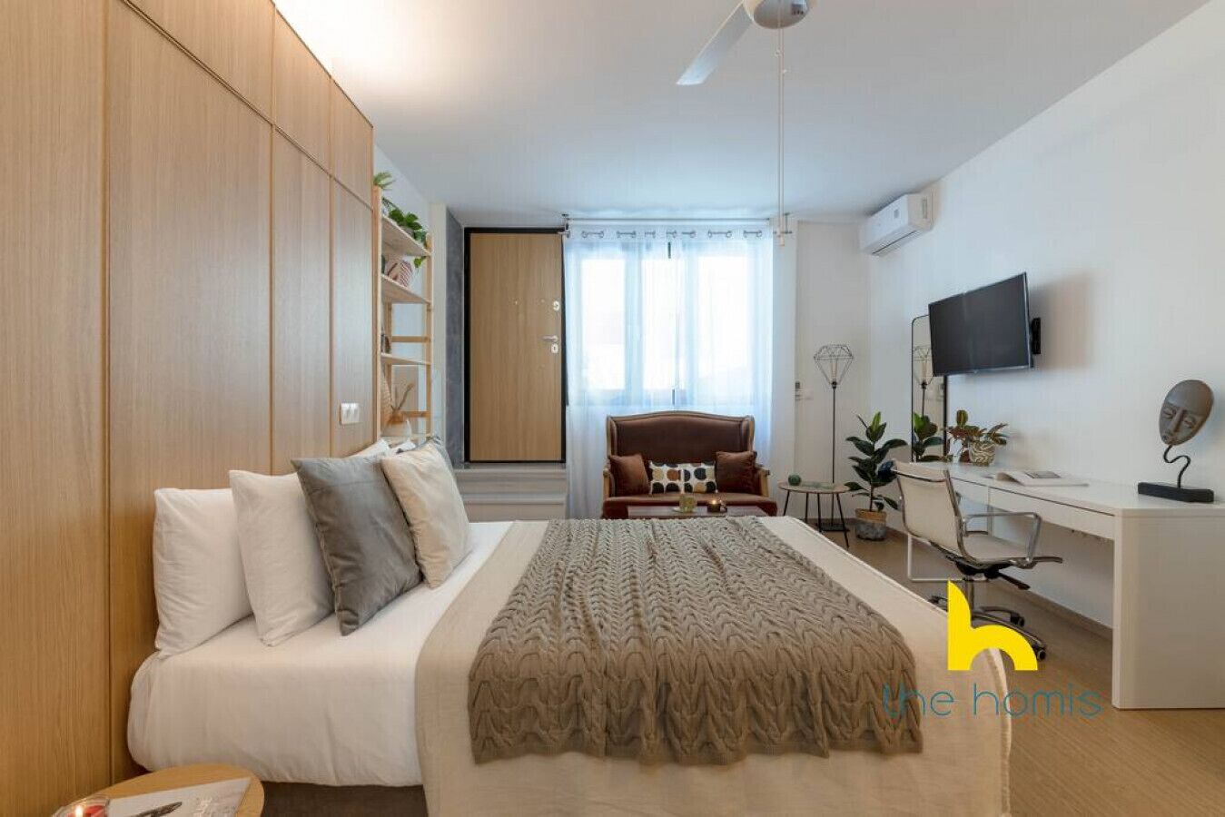 A bedroom with a bed, a desk, a chair, a TV, and a wardrobe.