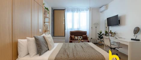 A bedroom with a bed, a desk, a chair, a TV, and a wardrobe.