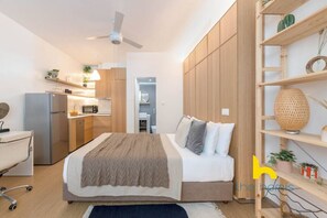 A modern bedroom with a bed, a desk, a chair, a wardrobe, and a shelf with plants. - Kypseli's Dreamy Studio Your Cosy Greek Oasis! (Athina)
