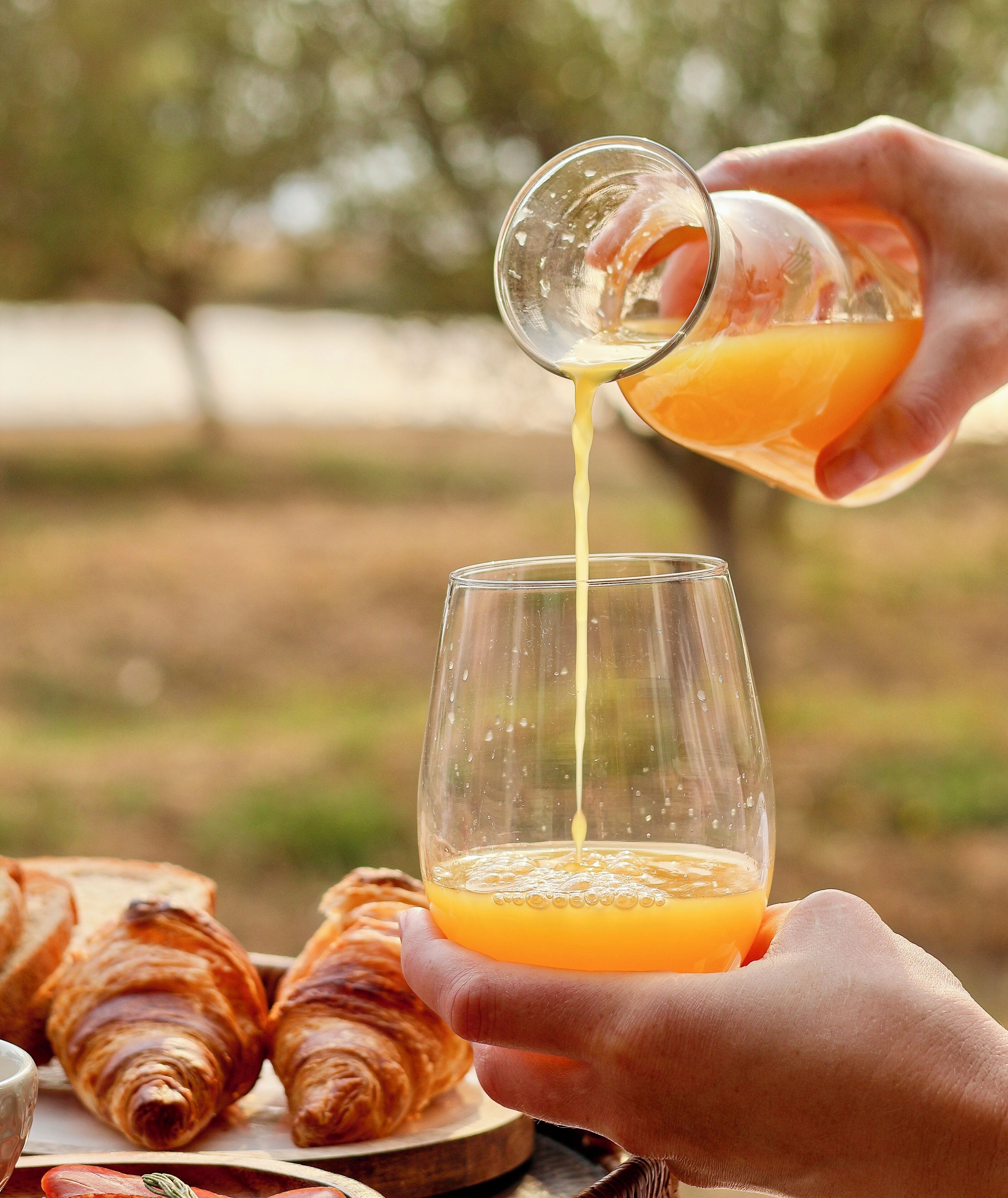 Una persona sirviendo jugo de naranja en un vaso.