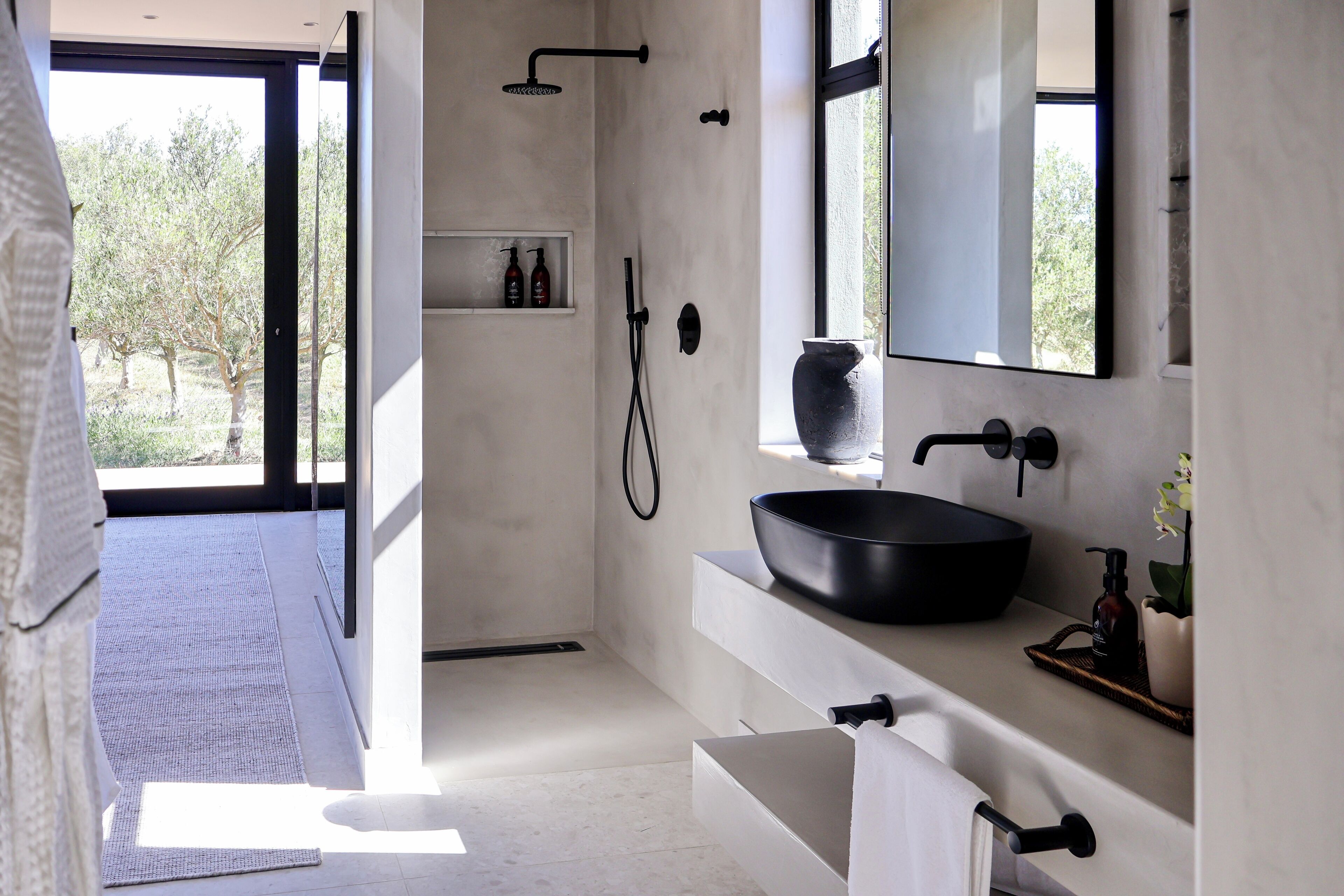 Un bany modern amb un gran rentapans al color negre, un mirall i una zona de dutxa.