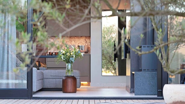 A modern living room with a grey sofa, a coffee table, and a vase of flowers. - Olijvenkraal Winelands Lodge (Paarl)