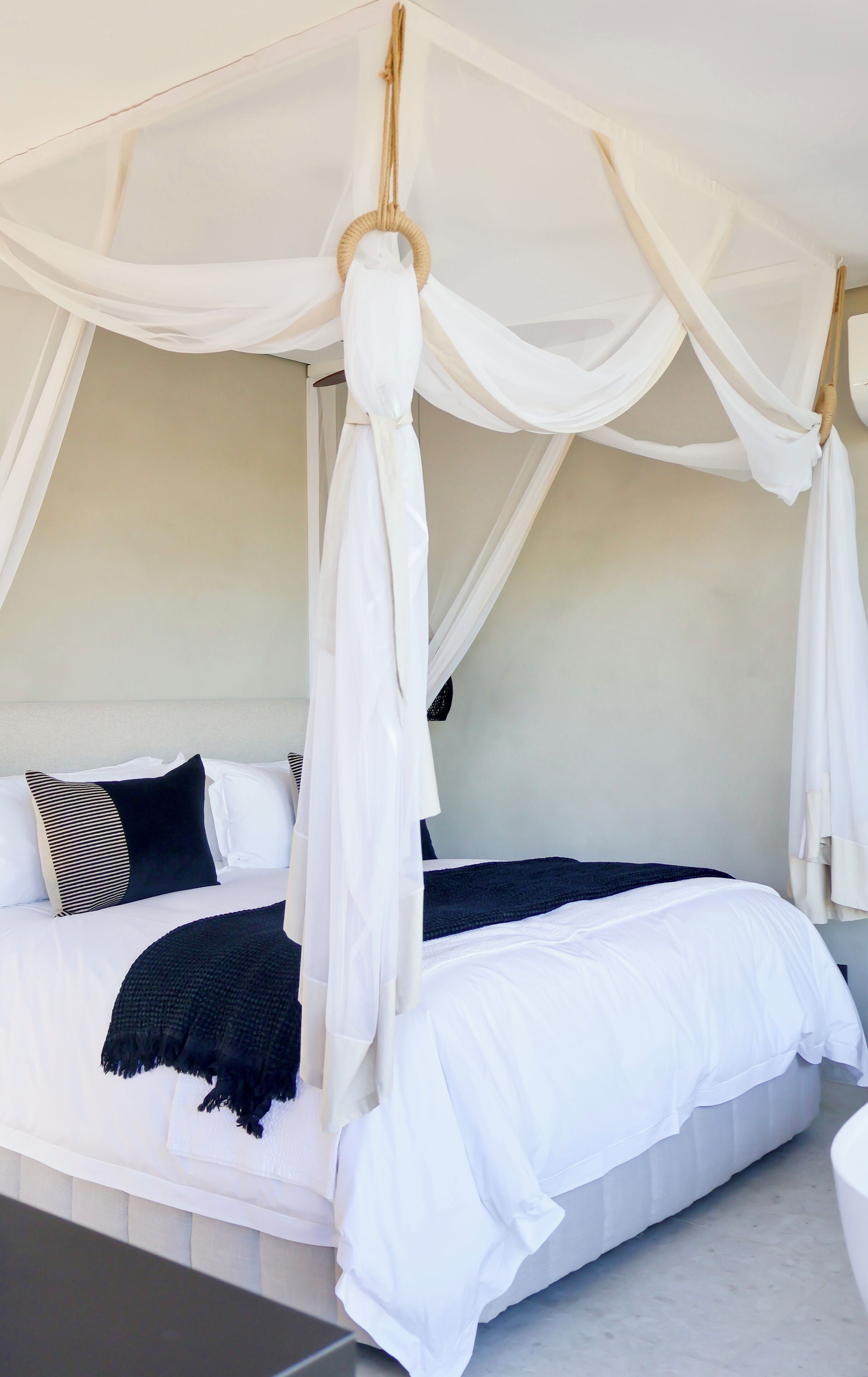 Un dormitorio con cama a dosel, ropa de cama blanca y una manta negra.