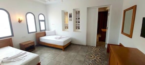 A bedroom with a bed, a nightstand, a dresser, a mirror, and a door leading to another room. - DAR AMMAR (El Djem)