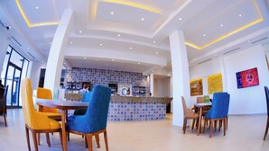 A modern hotel lobby with a bar area, seating arrangements, and artwork on the walls. - DAR AMMAR (El Djem)