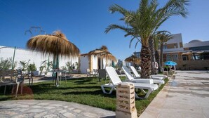 A resort with outdoor seating, palm trees, and a building with a dome. - DAR AMMAR (El Djem)