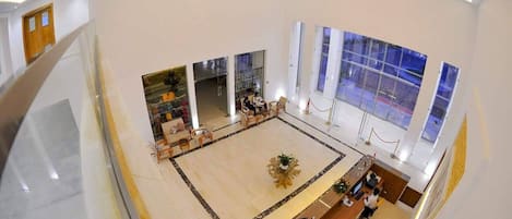 Un hall amplio con mostrador de recepción, zona de estar y ventanas grandes.