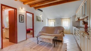 Un espacio habitable compacto con sofá, una mesita, una zona de cocina y un acceso a un dormitorio.