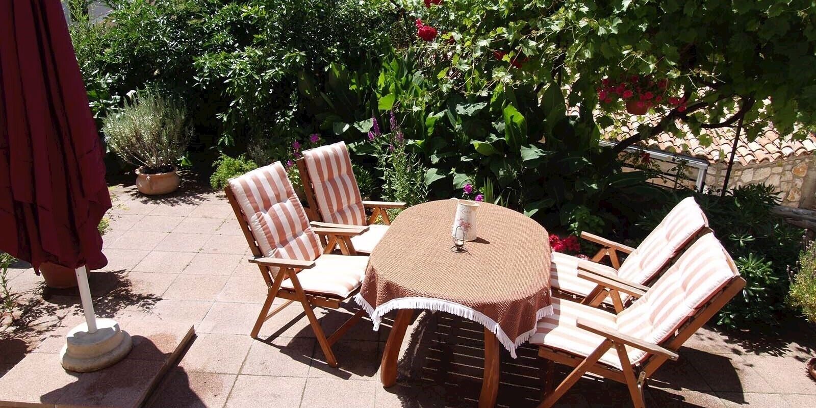 Eine Terrasse im Freien mit einem runden Tisch und sechs gestreiften Stühlen.