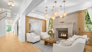 A spacious living room with a fireplace, white sofas, and a wooden floor. - Spaulding Ave Farmhouse - Bespoke LA Home w/ Pool & Home Theater (Los Angeles)